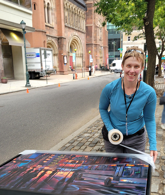 Sarah Pollock wrapping a cityscape oil painting